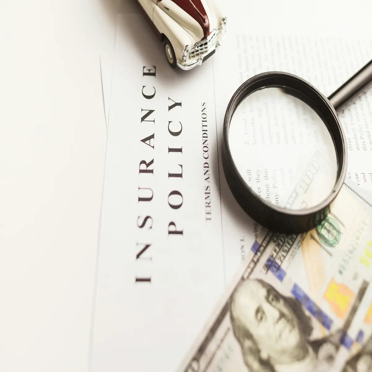 Insurance policy document with a magnifying glass and cash