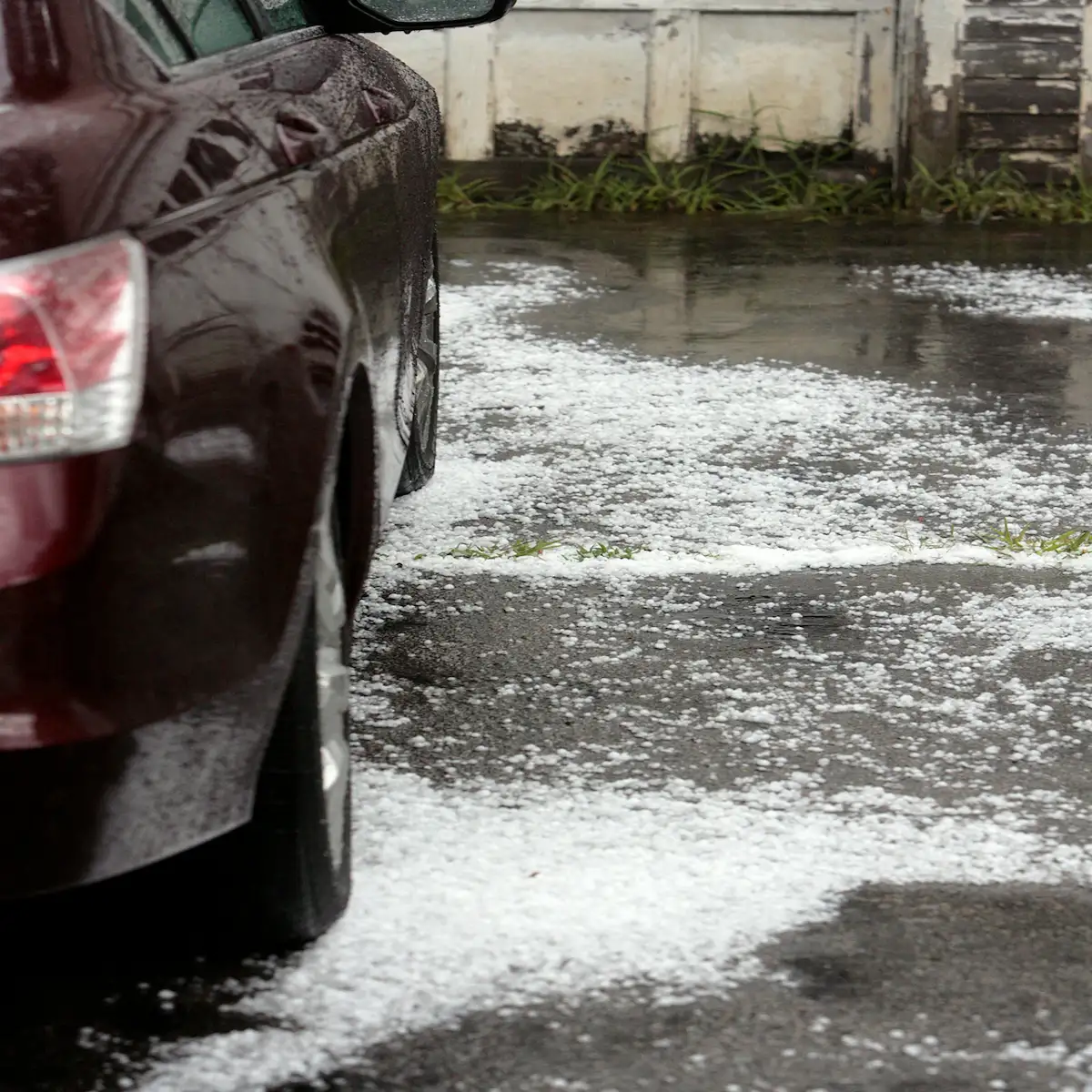 Hail on the ground next to a car after a West Texas storm